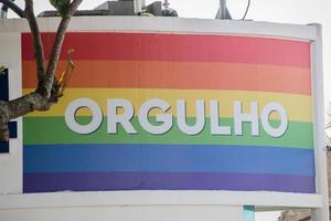 Regenbogenflagge mit dem Wort Stolz geschrieben auf Portugiesisch am Strand der Copacabana in Rio De Janeiro. foto