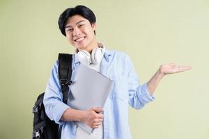 männlicher asiatischer Student, der seine Hand zu seiner Linken hält foto