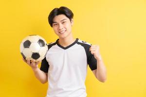 der asiatische mann hält den ball und zeigt triumphierend