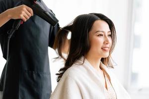 asiatische Frau mit glücklichem Ausdruck beim Friseur im Salon