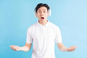 ein Foto eines gutaussehenden asiatischen Mannes mit einem überraschten Ausdruck, der Musik hört