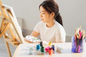 junges Mädchen, das auf dem Boden sitzt und lernt, selbst zu zeichnen foto