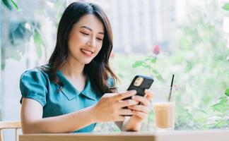 junge asiatische Frau mit Smartphone, um im Café zu arbeiten