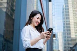 junge asiatische Frau mit Smartphone, um an ihre Freunde zu schreiben foto
