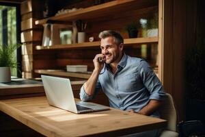 ein Mann im Hemd und Jeans auf seine Laptop reden auf ein Telefon. foto