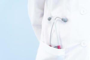 ein Arzt im weißen Kittel mit Stathoskop in der Tasche auf blauem Hintergrund foto