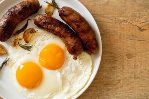 hausgemachtes doppeltes Spiegelei mit gebratener Schweinswurst - zum Frühstück foto