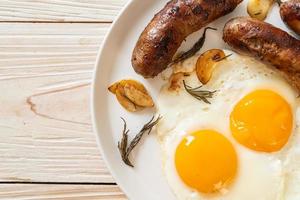 hausgemachtes doppeltes Spiegelei mit gebratener Schweinswurst - zum Frühstück foto