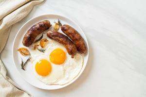 hausgemachtes doppeltes Spiegelei mit gebratener Schweinswurst - zum Frühstück foto