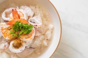 Porridge oder gekochte Reissuppe mit Meeresfrüchten von Garnelen, Tintenfisch und Fisch in einer Schüssel foto