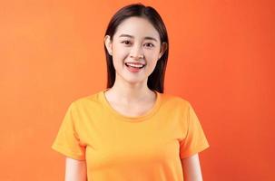 Bild der jungen asiatischen Frau mit orangefarbenem T-Shirt auf orangefarbenem Hintergrund foto