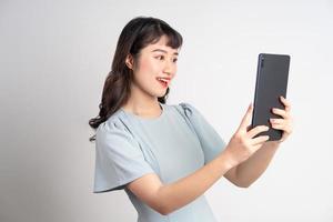 junge asiatische Frau mit Tablet auf weißem Hintergrund foto