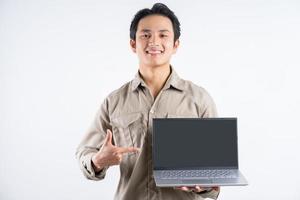 Porträt eines männlichen Mechanikers, der mit Laptop steht und darauf auf weißem Hintergrund zeigt foto