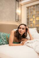 ein schön asiatisch Frau ist entspannend auf ein Weiß Bett während tragen bilden und Kleid foto