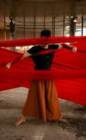 ein asiatisch Mann Stehen stolz unter das rot Stoff Das baumelt im ein alt Gebäude foto