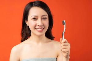 schöne asiatische Frau mit Zahnbürste im Hintergrund foto