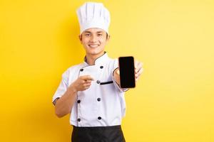 Der asiatische Küchenchef zeigte mit dem Finger auf das Handy, das er in der Hand hielt foto