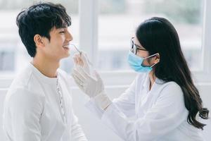 asiatische Ärztin, die die Zähne eines Patienten überprüft foto
