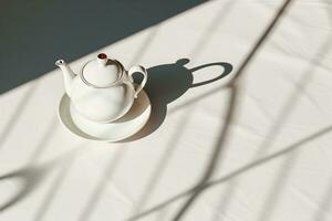 Modernist Teekanne Design auf ein Weiß Tischdecke, das Teekannen Schatten Dehnen lange im das schwer Beleuchtung, reflektieren ein zeitgenössisch ästhetisch und Fett gedruckt Stil. foto