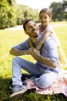 Vater mit Tochter, die Spaß auf dem Gras im Park hat