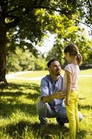 Vater mit Tochter, die Spaß auf dem Gras im Park hat