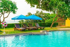 Liegestühle oder Poolbetten mit Sonnenschirmen um den Pool bei Sonnenuntergang
