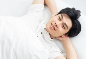 asiatischer Mann liegt im Bett und lächelt selbstbewusst smiling foto