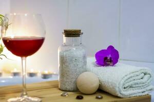 Spa-Schönheitssalon, Wellnesscenter. Spa-Behandlung Aromatherapie für den weiblichen Körper im Badezimmer mit einem Glas Wein, mit Kerzen, Ölen und Salz foto