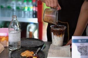 Mitarbeiter füllen Kaffee in Gläser, um Latte für Kunden zuzubereiten. foto