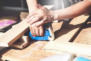 Unternehmer Holzarbeiten, die einen Tacker halten, um die Holzstücke nach Kundenwunsch zusammenzubauen. foto