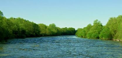 breit Fluss umgeben durch das Natur von Grün Bäume und Flüsse während das Tag foto