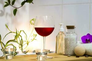 Spa-Schönheitssalon, Wellnesscenter. Spa-Behandlung Aromatherapie für den weiblichen Körper im Badezimmer mit einem Glas Wein, mit Kerzen, Ölen und Salz foto
