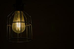Nacht Fotografie von das Licht Birne, weißglühend Lampe, ein Draht Glühfaden Das ist erhitzt bis um es leuchtet. mit Metall Käfig isoliert auf schwarz Hintergrund. foto