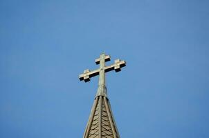 Kreuz Stehen auf ein Kirche Dach ,geometrisch Zahl bestehend aus von zwei sich überschneiden Linien oder Riegel gegen das Blau Himmel. foto