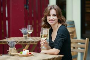 schön jung Frau Trinken Weiß Wein auf das Terrasse von ein Restaurant foto