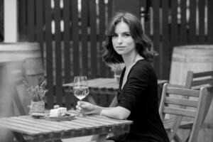 schön jung Frau Trinken Weiß Wein auf das Terrasse von ein Restaurant foto