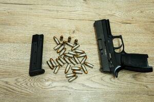 Pistole und Kugeln und Zeitschriften Lügen auf ein hölzern Tabelle foto