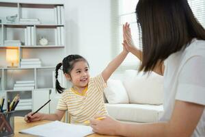 süß wenig Kind und Mama Hände Herstellung geben mich fünf während Gemälde mit bunt malt. asiatisch Mädchen und Mutter mit Wachsmalstift Zeichnung Farbe. Tochter und Mama tun Hausaufgaben Färbung Karikatur Figuren. foto