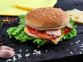 leckerer Hamburger auf Holzhintergrund mit Gemüse und Gewürzen