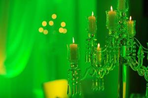 Hochzeitsdekoration. Kristallkandelaber mit Kerzen in grünem Licht foto