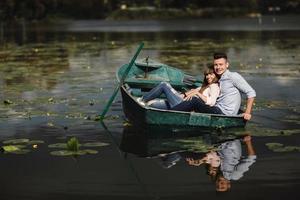 einfach nur Entspannen. Schönes junges Paar, das ein romantisches Date beim Rudern eines Bootes genießt. Liebespaar, das auf einem See ruht, während es ein grünes Boot fährt. Romantik. foto