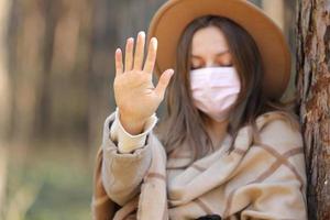 Frau in medizinischer Schutzmaske stoppt Virus draußen im Wald. Luftverschmutzung, Umweltkonzept selektiver Fokus