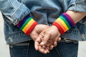 asiatische dame mit regenbogenflaggenarmbändern, symbol des lgbt-stolzmonats, feiert jährlich im juni die sozialarbeit von schwulen, lesbischen, bisexuellen, transgendern und menschenrechten. foto