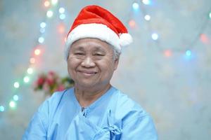 asiatische ältere oder ältere alte Dame Patientin mit Weihnachtsmann-Helferhut sehr glücklich in Weihnachts- und Neujahrsfeier-Festival-Feiertagsparty im Krankenhaus. foto