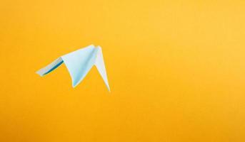 Sommertourismus, Origami-Papierflieger auf gelbem Hintergrund mit Kopierraum