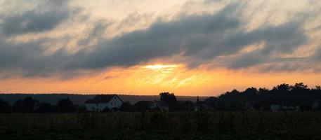 Morgensonnenaufgang über dem Dorf, die erwachende orangefarbene Sonne außerhalb der Stadt foto