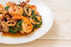 gebratene Meeresfrüchte von Garnelen und Tintenfisch mit thailändischem Basilikum - asiatische Küche foto