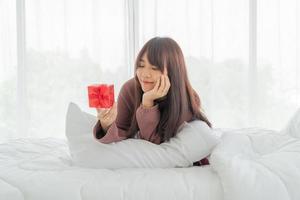 asiatische Frau freut sich über eine Geschenkbox oder ein Geschenk foto