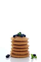 Stapel von köstlich Pfannkuchen mit frisch Blaubeeren, Minze Blatt, und Ahorn Sirup foto
