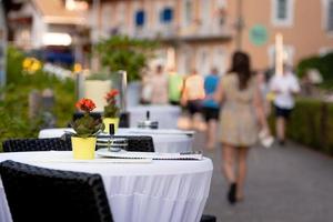 Cafétische auf der Straße. im Hintergrund ist eine Straße mit menschlichen Silhouetten. foto